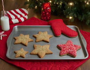 christmas cookies on the table, Seasonal baking setup showing a metal cookie sheet with tree shaped cookies, star cookies, a candy cane and a red quilted oven mitt, evoking Christmas treats