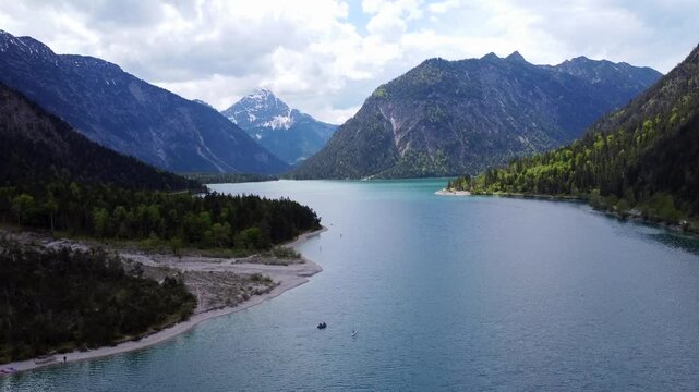 Majestic aerial view of Lake Plansee with turquoise water and winding road in the Tyrolean Alps, Austria.