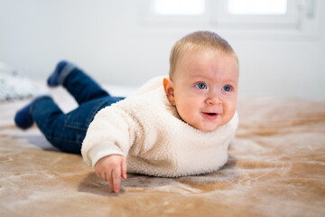 Fototapeta premium Adorable baby enjoying tummy time on soft blanket