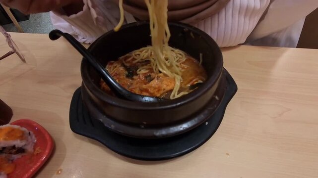 Videography of a woman's hands pinching and slurping ramen noodles with chopsticks. Footage of a woman enjoying spicy ramen with chopsticks. Food Footage in 4K HD Resolution