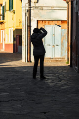 A shadow of a woman taking picture of an old colorful door 