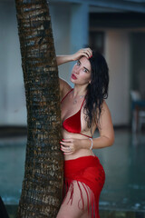 Confident Beauty in Red Swimwear by a Tropical Palm Tree
