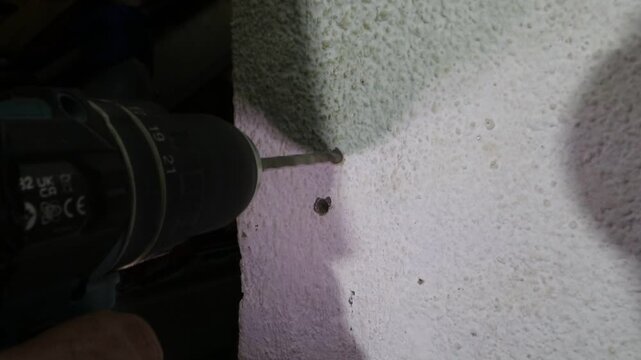Worker detail of how to drill a hole in a cement wall with power drill