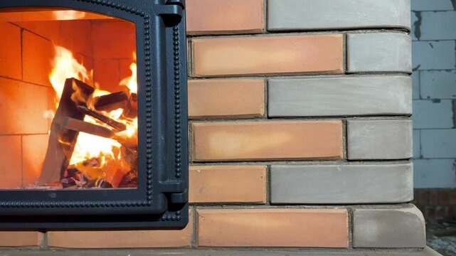 A fragment of brickwork of a heating stove and a firebox with a glass door. Test fire in a new heating stove. Stove construction.
