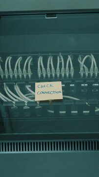 A hand placing a sticky note on a server rack in a data center that is stating to check connection.