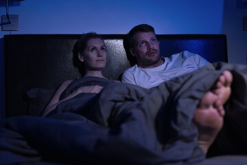 couple laying in the bed at home bedroom and watching TV together at late night