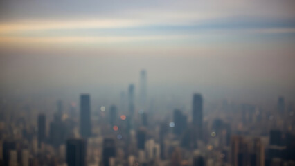 Fototapeta premium Blurred cityscape skyline with tall buildings under a hazy sky at dusk