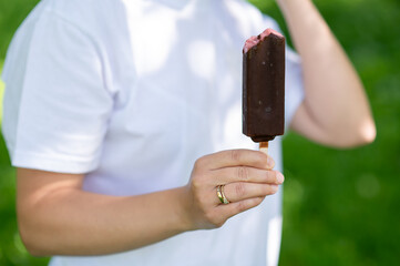 Woman holding chocolate ice cream on stick close up