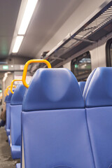 Empty blue seats with orange handles on modern train reflecting urban travel and daily commuting...