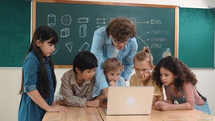 Caucasian teacher and diverse student looking at laptop at classroom. Cute multicultural children learning about coding program or generated program by using software while teacher teaching. Pedagogy. - Powered by Adobe