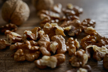 Obraz premium Walnuts scattered on a wooden surface with whole walnuts in the background during daylight