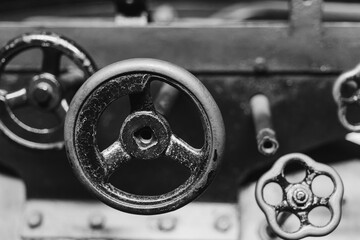 Industrial machinery showcasing detailed gears and valves in black and white, capturing the essence of vintage engineering in a workshop setting