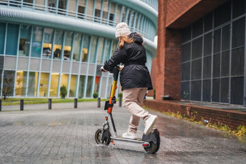 Moving electric scooter along wet street during rainy commute. Leaning into turn for micromobility transport. Urban mobility ride continues on slippery pavement in bad weather. Last mile travel.