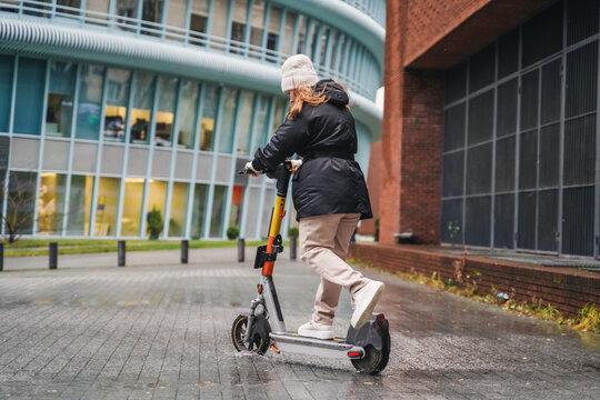 Moving electric scooter along wet street during rainy commute. Leaning into turn for micromobility transport. Urban mobility ride continues on slippery pavement in bad weather. Last mile travel.