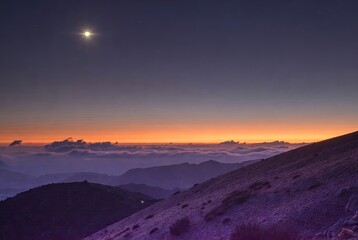 Celestial glow over majestic mountain range as twilight paints the horizon in vibrant hues