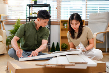 Fototapeta premium couple assembling wooden furniture together, Young asian couple assembly a new furniture at home
