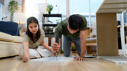 Asian adult couple assembling wooden furniture together in modern living room create new home decor DIY project happiness