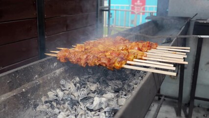 Grilling sticks in urban setting, Rows of meat skewers roasting amid smoke, Series of metal skewers over hot coals with consistent rotation and smoky atmosphere