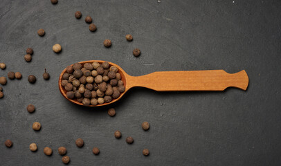 Allspice berries in a wooden spoon