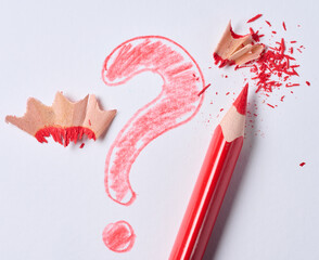 Red pencil and a drawn question mark with shavings on a white background