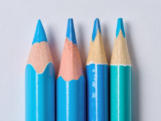 A row of blue wooden drawing pencils with sharp tips on a white background