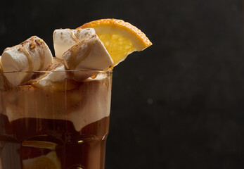 A glass of hot chocolate with white marshmallow pieces on a wooden table