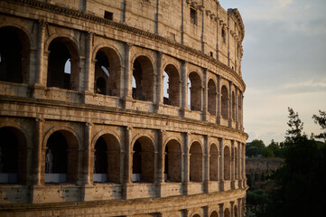 Obraz premium The iconic Roman Colosseum at sunset featuring the ancient stone arches and monumental architecture of the historic Flavian Amphitheatre in Rome Italy