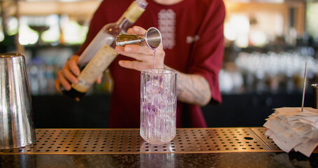 Mixologist work. Making cocktail. Bartender pouring sweet aroma color syrup from metal jigger to glass. Flavored refreshing drink.