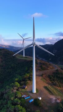 vertical video: orbiting drone Shot of Wind Turbines on a Mountain at sunset in Spain, renewable energy concept, green eco energy