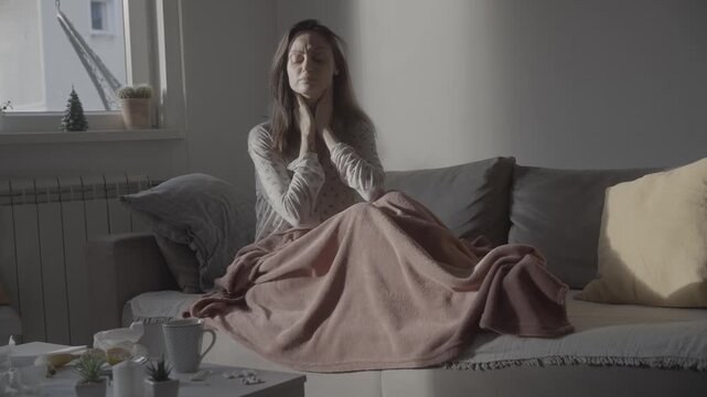 Caucasian woman suffering from sore throat sitting on sofa