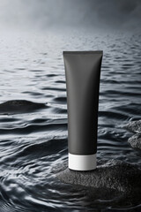 A black tube is placed on a rock above water that has ripples.