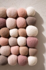 Soft wool felt balls in beige and white colors arranged in a grid pattern.