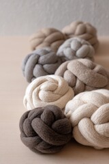 Multicolored wool felt balls in various sizes arranged in an abstract vertical structure on neutral background