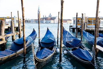 Venice, Italy - February 19, 2025: Gondolas lined up at a dock in Venice, showcasing the iconic architecture and serene waters of the famous Italian city with vibrant reflections © HelgaQ