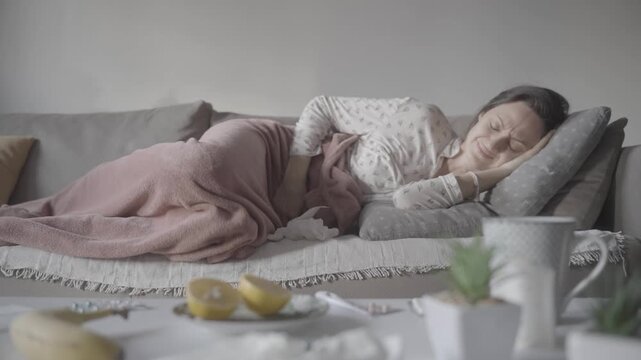 Sick, home and person suffering and holding belly on a couch and living room