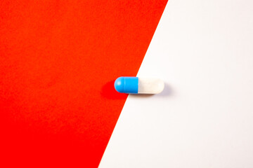 Blue and white pill on a red and white background. Medicine concept.