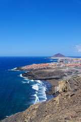 Aerial view of Tenerife beautiful coastline near El Medano, sunny summer day, Canary Islands, overtourism protests concept, Spain