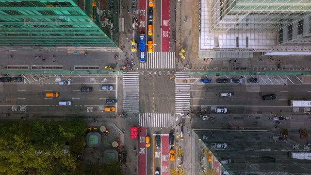 Cinematic aerial top down shot of New York City, New York showing busy intersection, crosswalks, yellow taxis, traffic lanes, buildings and street markings creating a dynamic detailed urban scene