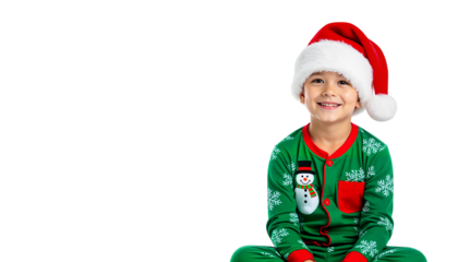 Smiling boy wearing Christmas pajamas and Santa hat isolated on a transparent background