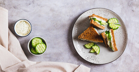 English sandwich with cucumber, butter and cheese on grain bread on a plate top view web banner