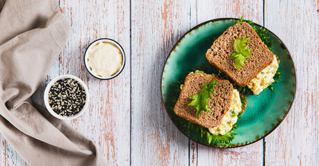 Eggs, avocado on lettuce leaves on toast on a plate on the table top view web banner