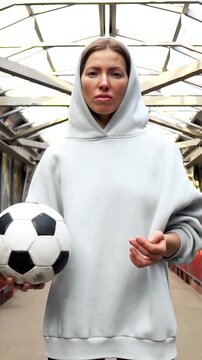 Young female football player hold soccer ball on urban background. Concept of active lifestyle