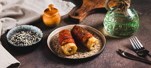 Baked banana roll with bacon on a plate on the table web banner