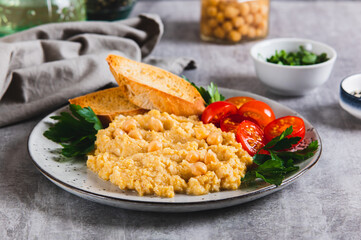 Chickpea puree, tomatoes, toast and greens on a plate on the table