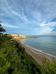 An azure wild beach with black rocks, an inaccessible shore with approaching boats.