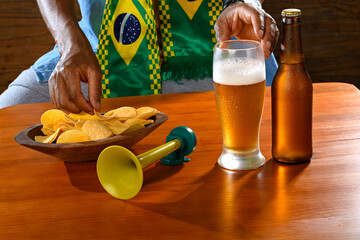 A Brazilian fan enjoying snacks and beer during a football match.
