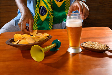 A Brazilian fan enjoying snacks and beer during a football match.