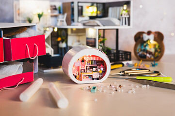 Glue and beads for decorating a tiny miniature house on a table