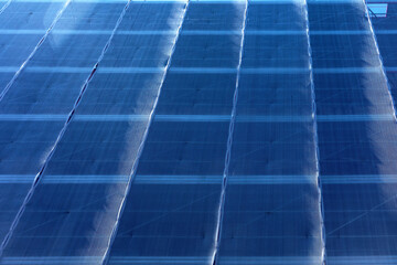 Building facade covered with blue construction safety netting secured by support beams. Intense blue mesh screening underlying structure, indicative of ongoing exterior maintenance or renovation