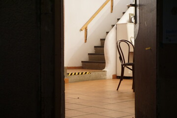 Geöffnete braune Holztür mit Ausblick auf ausgeleuchtete Innenausstattung von Café mit braunem...